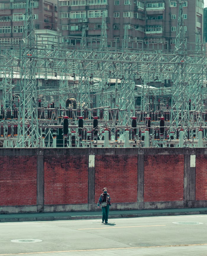 Man standing near an industrial electrical facility with urban backdrop